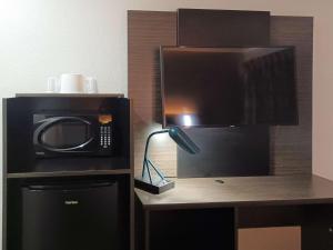 a microwave sitting on top of a desk with a lamp at Motel 6-Fresno, CA - Blackstone North in Fresno