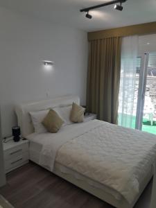 a bedroom with a large white bed with a window at Apartments Stojanovic in Ulcinj