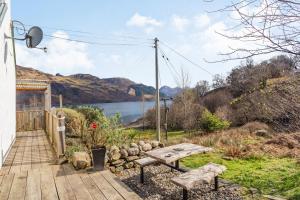 a wooden deck with a bench and a view of a lake at Druidaig Cottage in Letterfearn
