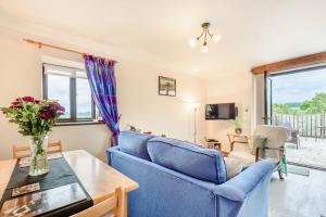 a living room with a blue couch and a table at Ystabl - Stable in Llanddulas