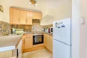uma cozinha com armários de madeira e um frigorífico branco em Ystabl - Stable em Llanddulas