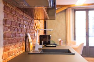 cocina con fregadero y pared de ladrillo en Ferrari Suites, en Valladolid