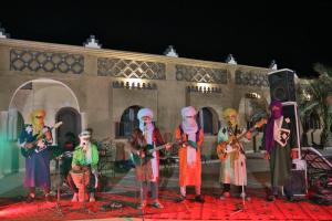 a group of people playing instruments on a stage at Residence Touristique Merzouga in Merzouga
