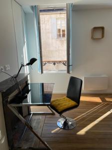 Cette chambre comprend une chaise, un bureau et une fenêtre. dans l'établissement Le studio de la Fosse Dionne, à Tonnerre