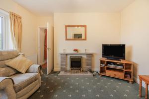 a living room with a couch and a tv and a fireplace at Meadow Lea in Leominster