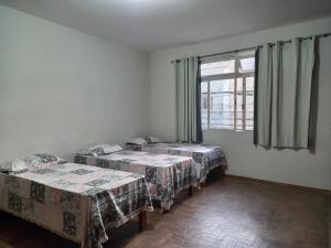 Cette chambre comprend 2 lits et une fenêtre. dans l'établissement Casa do Juá 2, à Lavras
