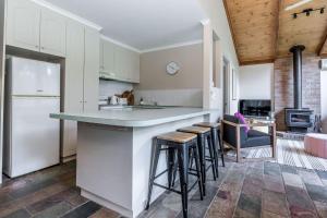 a kitchen with a counter and stools at Beach Scene on Streeton in Inverloch +10 photos