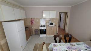 a kitchen with white cabinets and a table and a microwave at Apartman Progresso in Valjevo