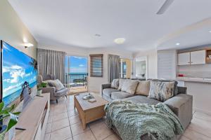 a living room with a couch and a tv at Casa Oceana - Airlie Beach in Airlie Beach