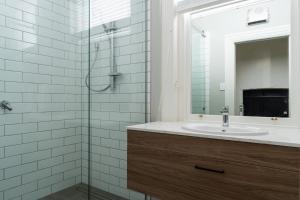 a bathroom with a sink and a shower with a mirror at Luxury Apartment on Stuart in Dunedin