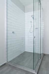a bathroom with a glass shower with white tiles at Star Struck on Stuart in Dunedin