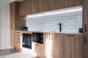 a kitchen with wooden cabinets and a white tile wall at Star Struck on Stuart in Dunedin