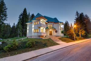 a large white house with a green roof on a street at Apartmani Bijelic in Žabljak