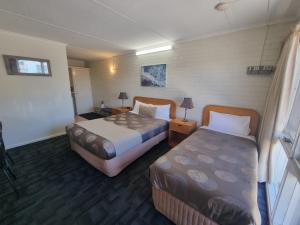 a hotel room with two beds and a table at Hacienda Motel Geelong in Geelong
