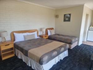 a hotel room with two beds and two lamps at Hacienda Motel Geelong in Geelong