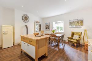 a kitchen and dining room with a table and a clock on the wall at Gardeners Cottage in Bellingham