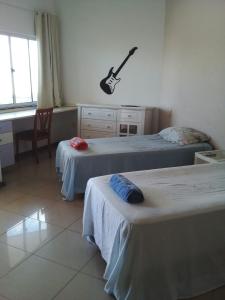 1 dormitorio con 2 camas y una guitarra en la pared en Hostel e Pousada do Bosque, en Rio Branco