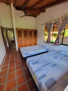 two beds in a room with two windows at Finca Hacienda el Castillo Santa Fe de Antioquia in Santa Fe de Antioquia