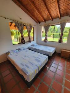 two beds in a room with large windows at Finca Hacienda el Castillo Santa Fe de Antioquia in Santa Fe de Antioquia