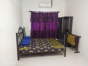 een bed in een kamer met een paars gordijn bij Ainur Homestay in Melaka