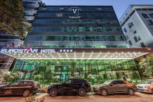 hotel z samochodami zaparkowanymi przed nim w obiekcie VH Eurostar Tirana Hotel Congress & Tirana Spa w Tiranie