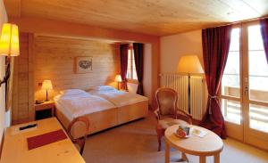 翁根Hotel Alpenrose Wengen - a family affair since 1881的一间配有床、桌子和椅子的酒店房间 更多37张照片