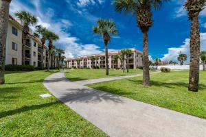 a walkway through the courtyard of a building with palm trees at Ocean Village Club D23 in Saint Augustine