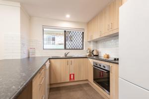uma cozinha com armários de madeira e uma bancada em Renas Court 2 em Forster
