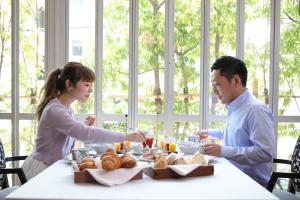 um homem e uma mulher sentados à mesa com comida em Kobe Kitano Hotel em Kobe