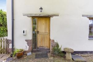 een houten deur op een wit huis met een bank bij The Yoke in Tedburn Saint Mary