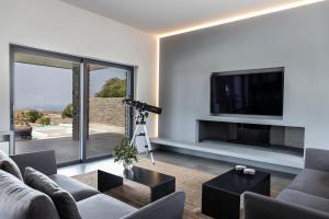 Villa drys II في Elliniká: غرفة معيشة مع أريكة وتلفزيون على الحائط