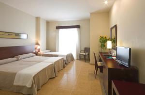 サン・ペドロ・デル・ピナタルにあるHotel Traíñaのベッド2台、薄型テレビが備わるホテルルームです。