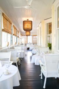 un comedor con mesas blancas y sillas blancas en The Edenton Collection-The Granville Queen Inn en Edenton