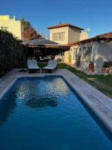 a swimming pool with two chairs next to a house at Chacras de Coria Relax in Ciudad Lujan de Cuyo