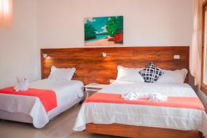 a bedroom with two beds with red and white sheets at Galápagos Isabela Hotel Loja in Puerto Villamil