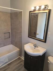 a bathroom with a sink and a tub and a mirror at Gateway Motel in Gananoque