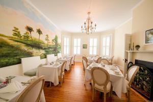 a restaurant with tables and chairs and a painting on the wall at The Edenton Collection-Captain's Quarters Inn in Edenton