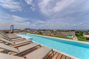 a swimming pool with chaise lounges and chairs at Prime 1 Bedroom Condo in Historic Downtown Playa del Carmen in Playa del Carmen
