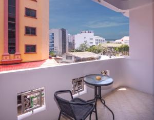 una mesa pequeña y una silla en un balcón con vistas en Robin's Nest Guesthouse & Restaurant, en Pattaya central