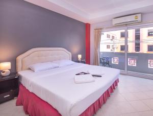 een slaapkamer met een groot wit bed en een groot raam bij Robin's Nest Guesthouse & Restaurant in Pattaya