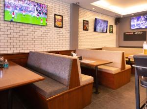 een restaurant met tafels en stoelen en een tv aan de muur bij Robin's Nest Guesthouse & Restaurant in Pattaya
