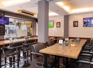 un restaurante con mesas de madera y sillas negras en Robin's Nest Guesthouse & Restaurant, en Pattaya central