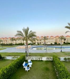a resort with a pool and two chairs and palm trees at Stella Heights villa - next to Marassi - North coast in El Alamein