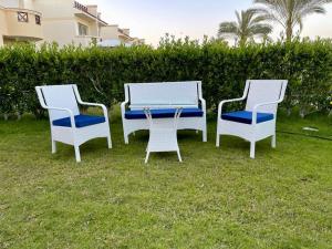 tres sillas y una mesa en el césped en Stella Heights villa - next to Marassi - North coast en El Alamein