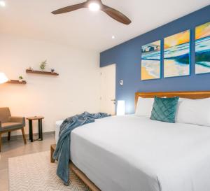 a bedroom with a white bed and a blue wall at Corasol Nick Price By PARR CONDOS in Playa del Carmen