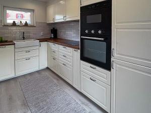 eine Küche mit weißen Schränken und schwarzen Geräten in der Unterkunft Holiday home ÄNGELHOLM IV in Ängelholm