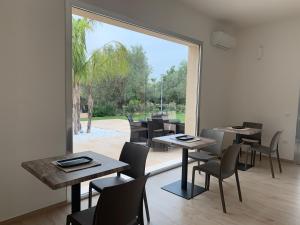 a dining room with tables and chairs and a large window at Resort Natura & Relax in Sestu