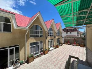 a house with a red roof and a patio at Tan Nuru Guest House Гостевой Дом Тан Нуру in Cholpon-Ata
