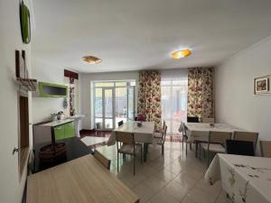 a living room with tables and chairs and a kitchen at Tan Nuru Guest House Гостевой Дом Тан Нуру in Cholpon-Ata