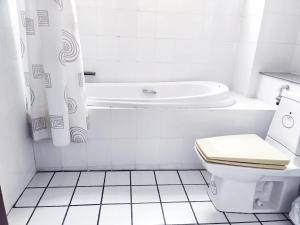 a bathroom with a tub and a toilet and a sink at Thong Paeka Hotel in Prasat